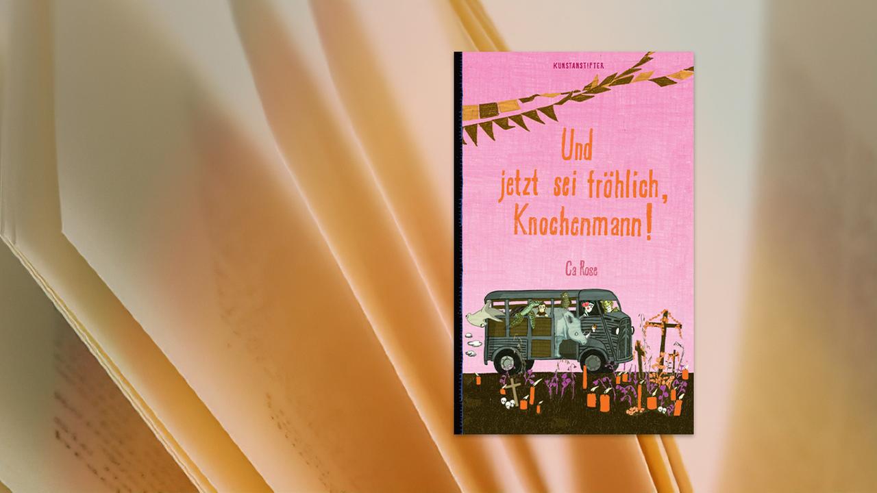 Auf dem Buchumschlag ist das gemalte Bild von einem Bus voller Tiere zu sehen, der auf einem bunt geschmückten Friedhof steht.