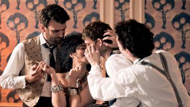 Drei Männer und eine Frau, eng umschlungen.