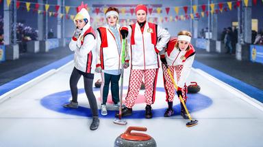 4 Frauen in Sportkleidung posieren auf einer Curlingbahn für die Kamera
