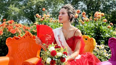 Eine junge Frau in festlicher Kleidung auf einem Sessel im Garten.