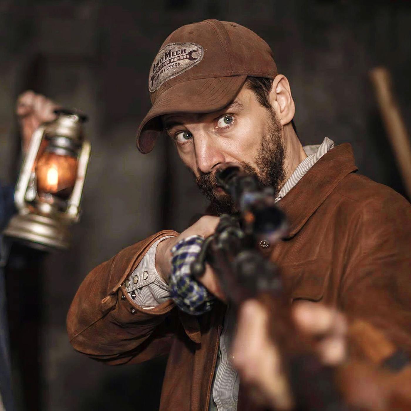 Zwei Männer in der Nacht; einer hält eine Laterne, der andere zielt mit einem Gewehr. 