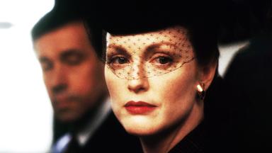 Sarah (Julianne Moore) mit einem schwarzen Gesichtsschleier aus Spitze vor ihrem Gesicht. Henry (Stephen Rea) ist etwas verschwommen im Hintergrund zu sehen.