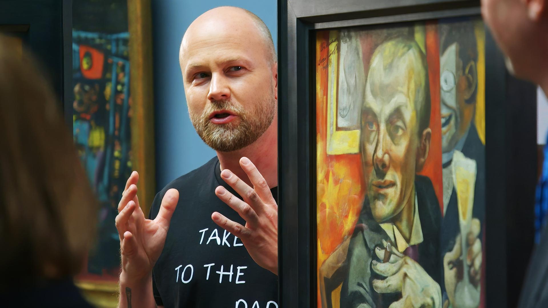 Ein Mann spricht vor einem Gemälde von Max Beckmann und gestikuliert mit den Händen.