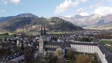 Das barocke Stift Admont liegt eingebettet in einer alpinen Landschaft, umgeben von bewaldeten Bergen und Wiesen.