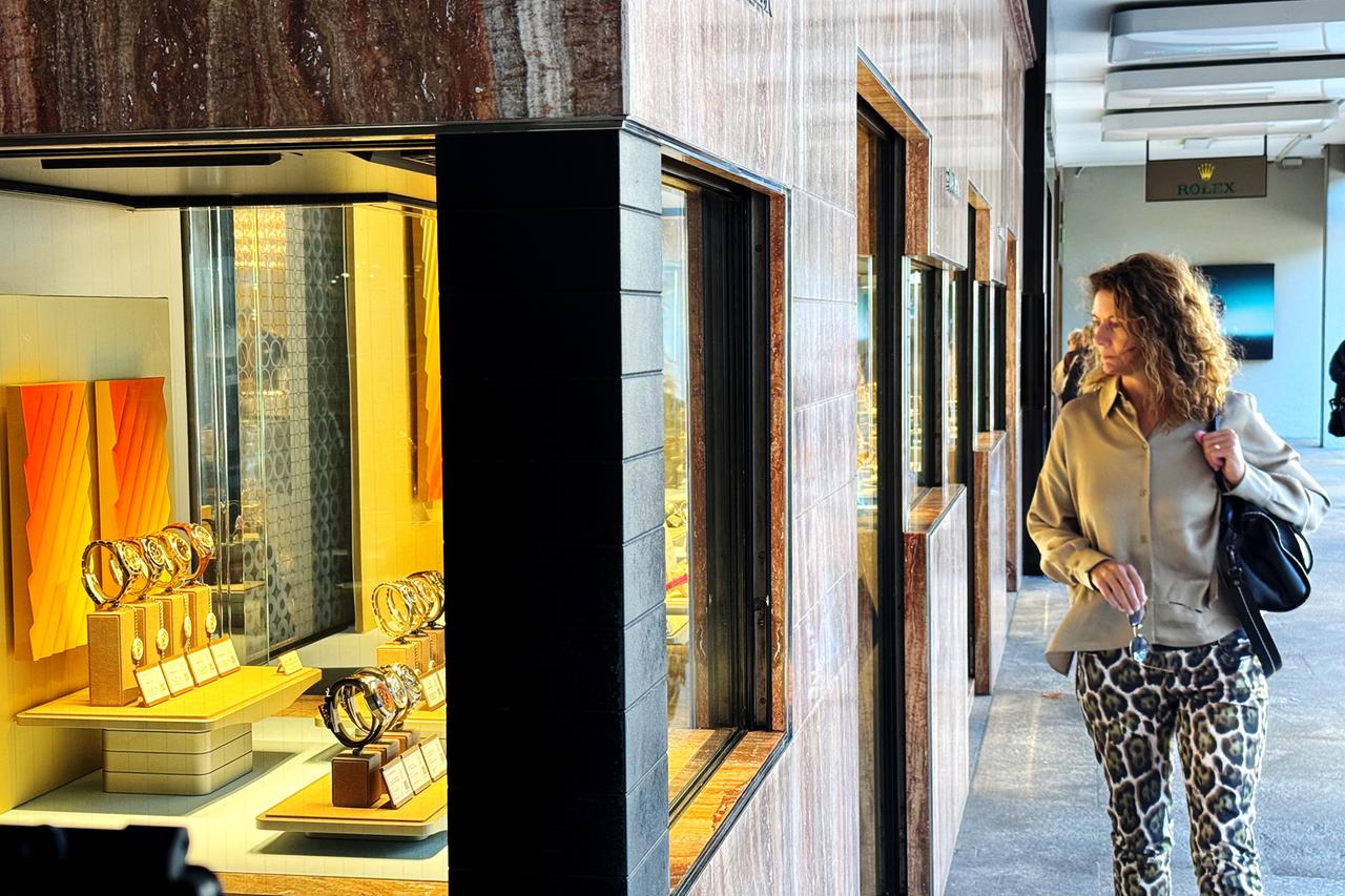 Eine Frau schlendert an einem Schaufenster mit teuren Uhren vorbei
