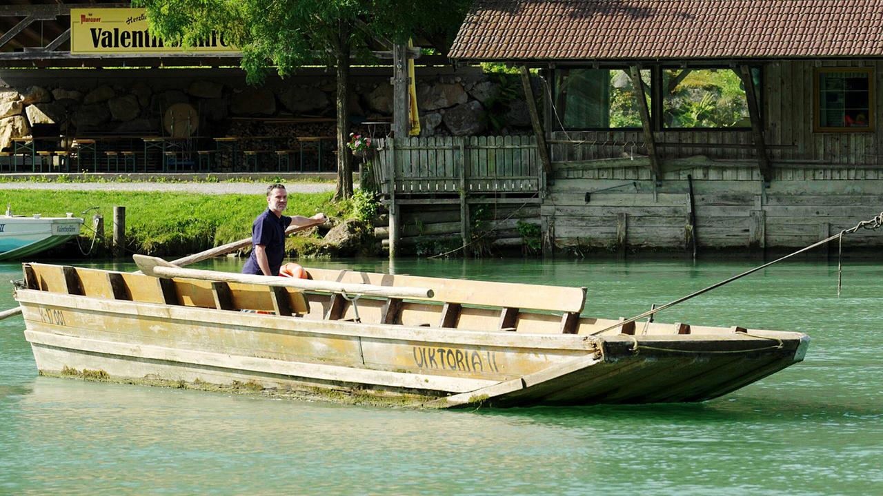 Ein Mann sitzt am Ruder einer kleinen Fähre