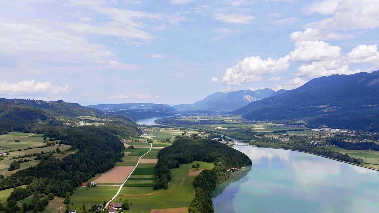 Ein Flusstal zwischen Wiesen und Bergen