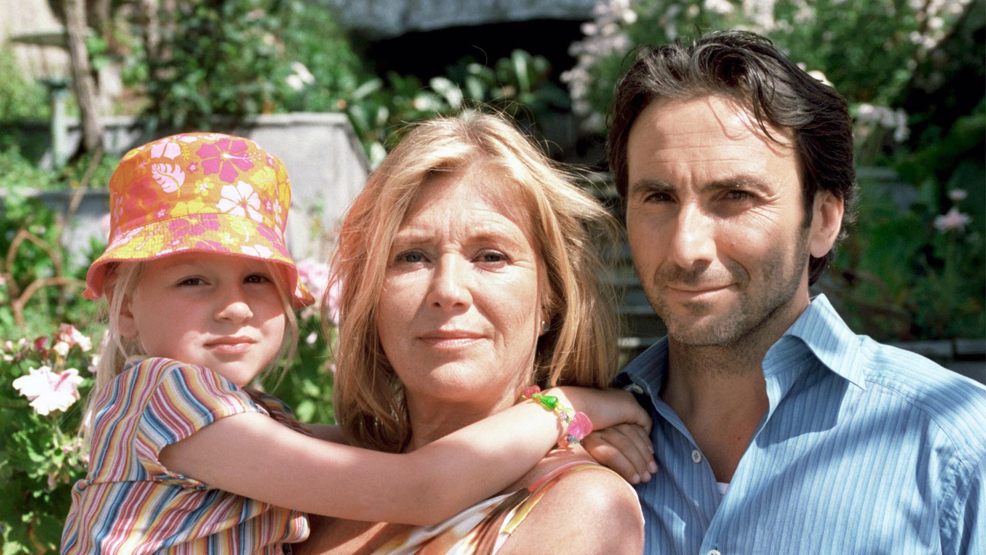 Ein Mann, eine Frau und ein Kind  blicken in Kamera. 