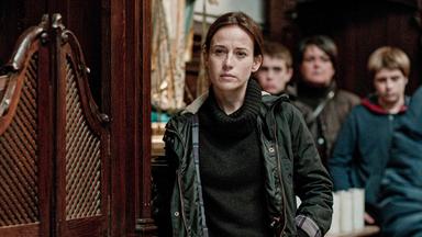 Frau steht in einer Kirche und sieht nach vorne.