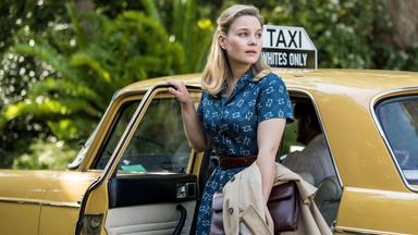 Eine blonde Frau steigt aus einem Taxi.