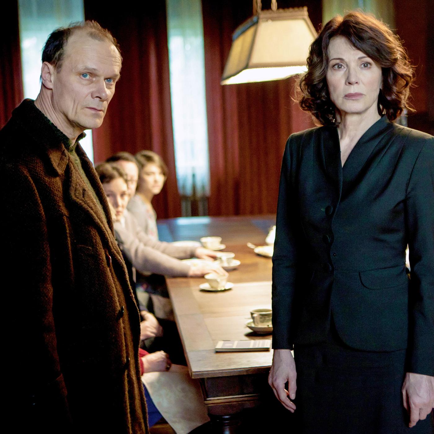 Ein Paar steht vor einem Tisch, an dem sich mehrere Menschen versammelt haben.