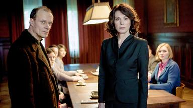 Ein Paar steht vor einem Tisch, an dem sich mehrere Menschen versammelt haben.