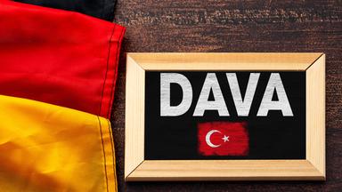 Neben der Deutschlandflagge liegt eine schwarze Tafel mit der Aufschrift DAVA und einer kleinen aufgemalten türkischen Flagge.