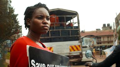 Junge Frau aus Uganda mit einem Schild bei einer Straßenkundgebung