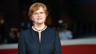 Eine Frau mit Brille und blauer Jacke und Schmuck