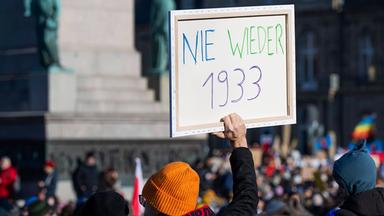 Frau hält Schild hoch: "Nie wieder 1933"