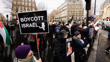 Demonstration gegen Israel in Paris. Eine Menschenmenge mit palästinensischen Flaggen und Schildern. Auf einem steht: Boycott Israel.