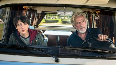 Ein Mann und ein Junge sitzen in einem Auto und schauen skeptisch.