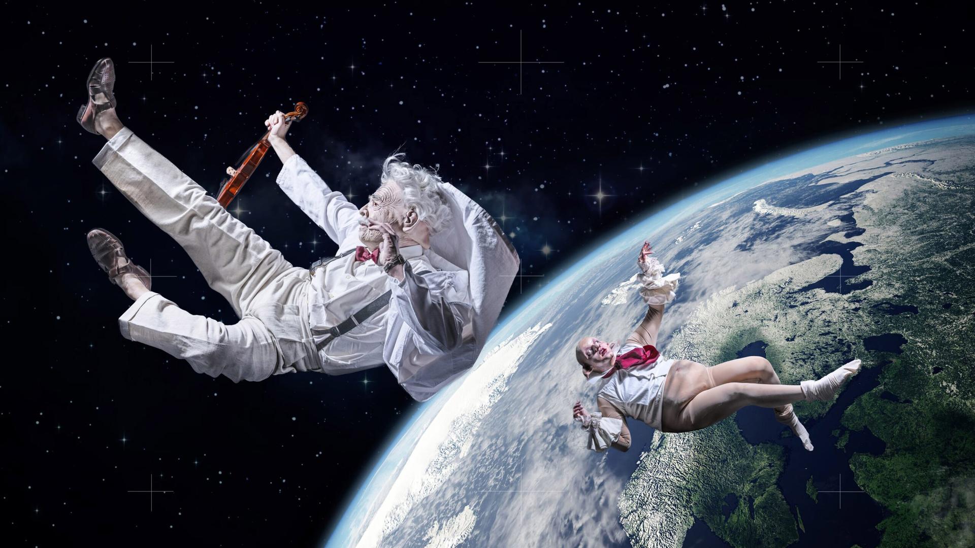 Zwei Personen schweben rücklings im All um die Erde. Ein weiß gekleideter Mann mit Bart hält dabei eine Geige in der Hand. 