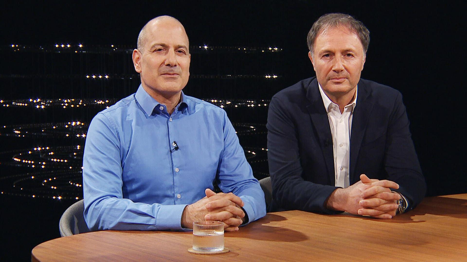 Zwei Männer sitzen an einem Holztisch