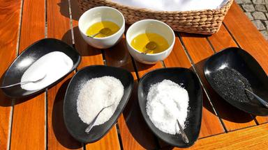 Einige Schüsseln Salz, ein Korb Brot und etwas Öl auf einem Tisch