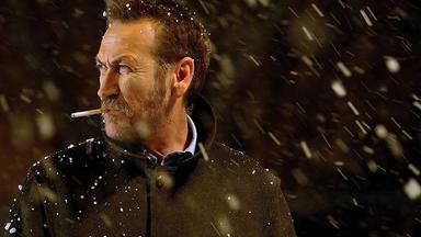 Kommissar Rocco Schiavone (Mario Giallini) steht mit einer Zigarette im Mund im Schneefall