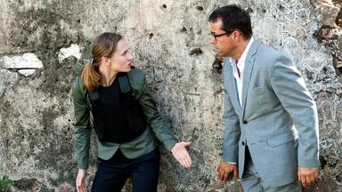 Anna-Maria (Alina Levshin) und Vernau (Jan Josef Liefers) stehen mit dem Rücken zu einer Felswand und streiten sich. Anna-Maria trägt eine schusssichere Weste.