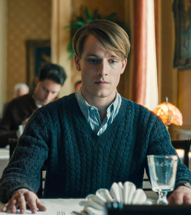 Junger Mann sitzt in einem Restaurant am Tisch.