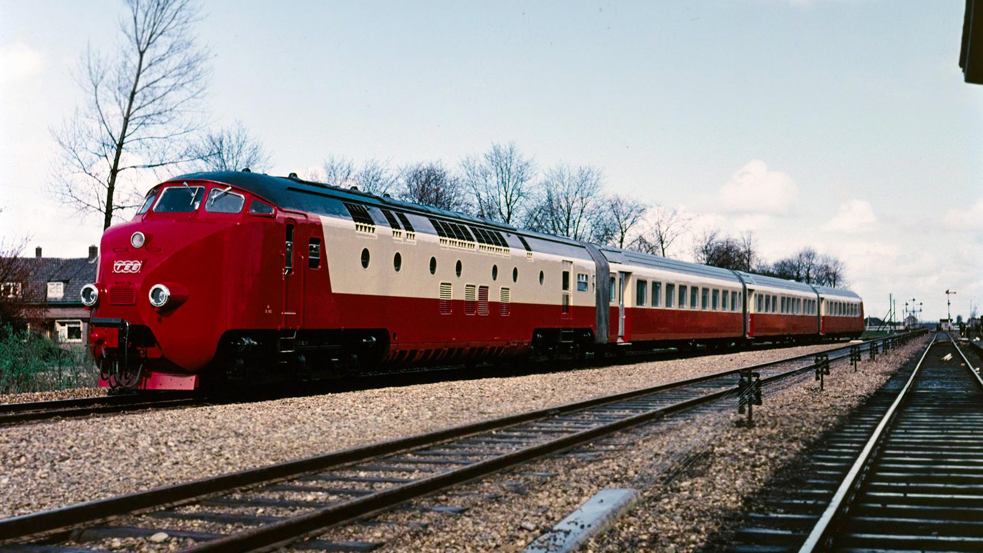 Ein rot-cremefarbener TEE-Triebzug mit mehreren Wagen steht auf einem Bahnhofsgleis, daneben verlaufen weitere Schienen.