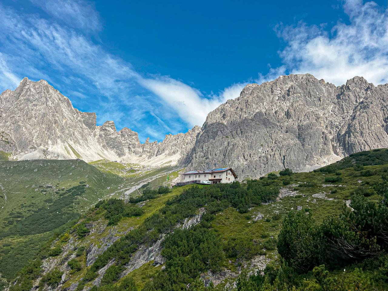 Alpenhütte aus der Froschperspektive um rahmt von felsigen Bergen