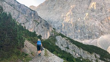 Wanderin von hinten gesehen auf einem steinigen Bergpfad