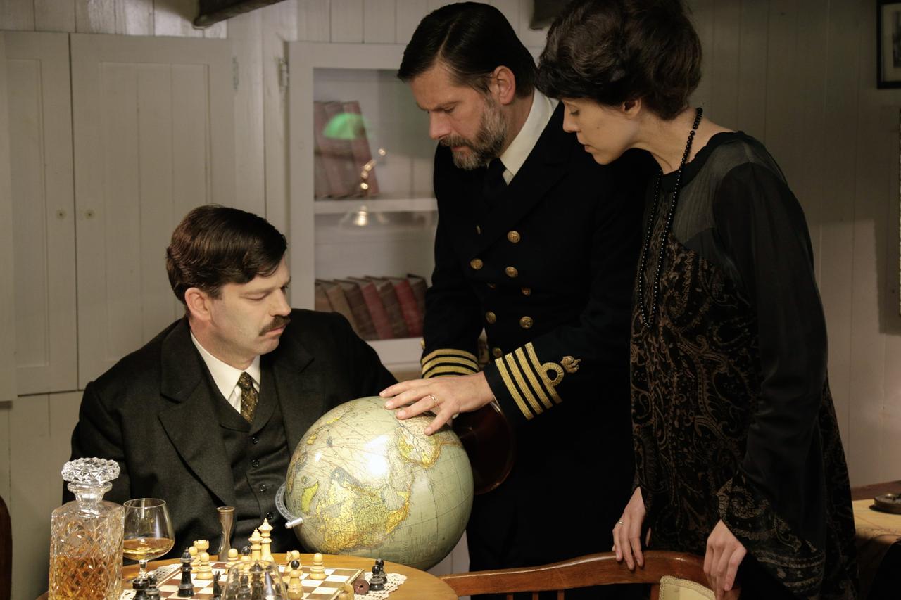 Zwei Männer und eine Frau schauen auf einen Globus.