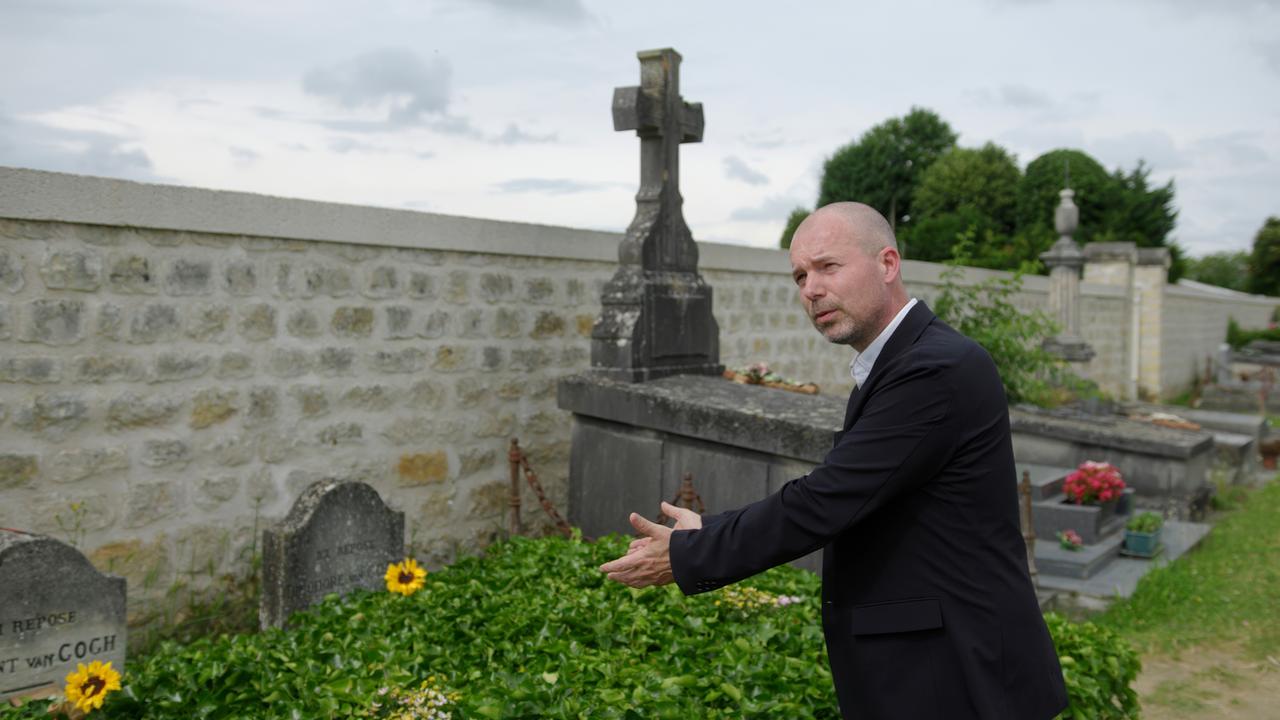 Mann deutet auf ein Grab.