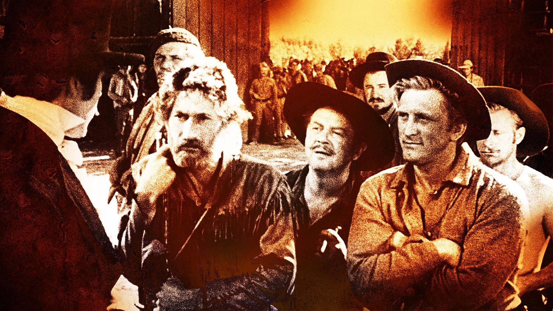 Mit anderen Männern steht der Trapper Jim Deakins (Kirk Douglas, vorne rechts) einem Mann mit Frack und Zylinder gegenüber. Im Hintergrund sind andere Männer und die Tore eines Forts zu sehen.