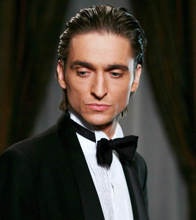 Ein junger Mann mit kantigem Gesicht in schickem Anzug.