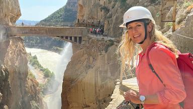 Eine blonde Frau steht in einer Schlucht.