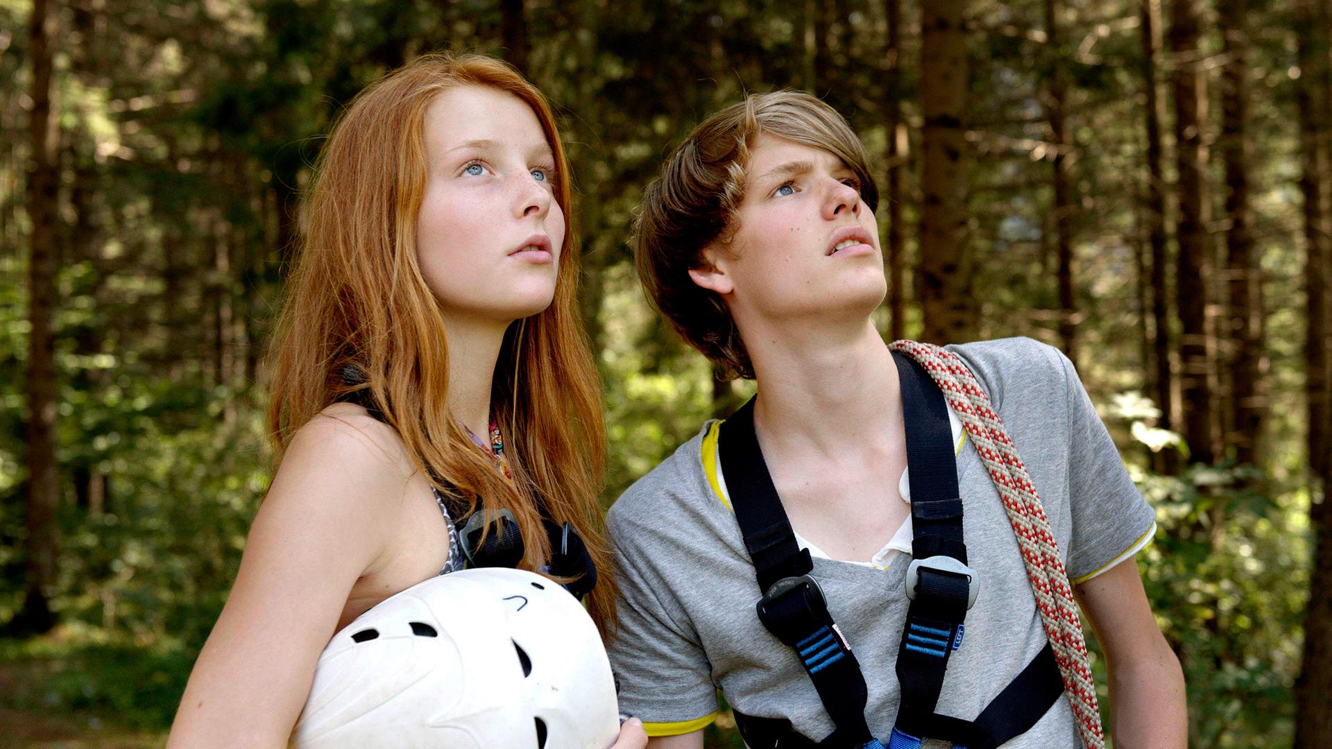 Toni (Til Schindler) und Valerie (Alina Strauß) schauen besorgt zu ihrem kletternden Mathelehrer Markus hinauf.