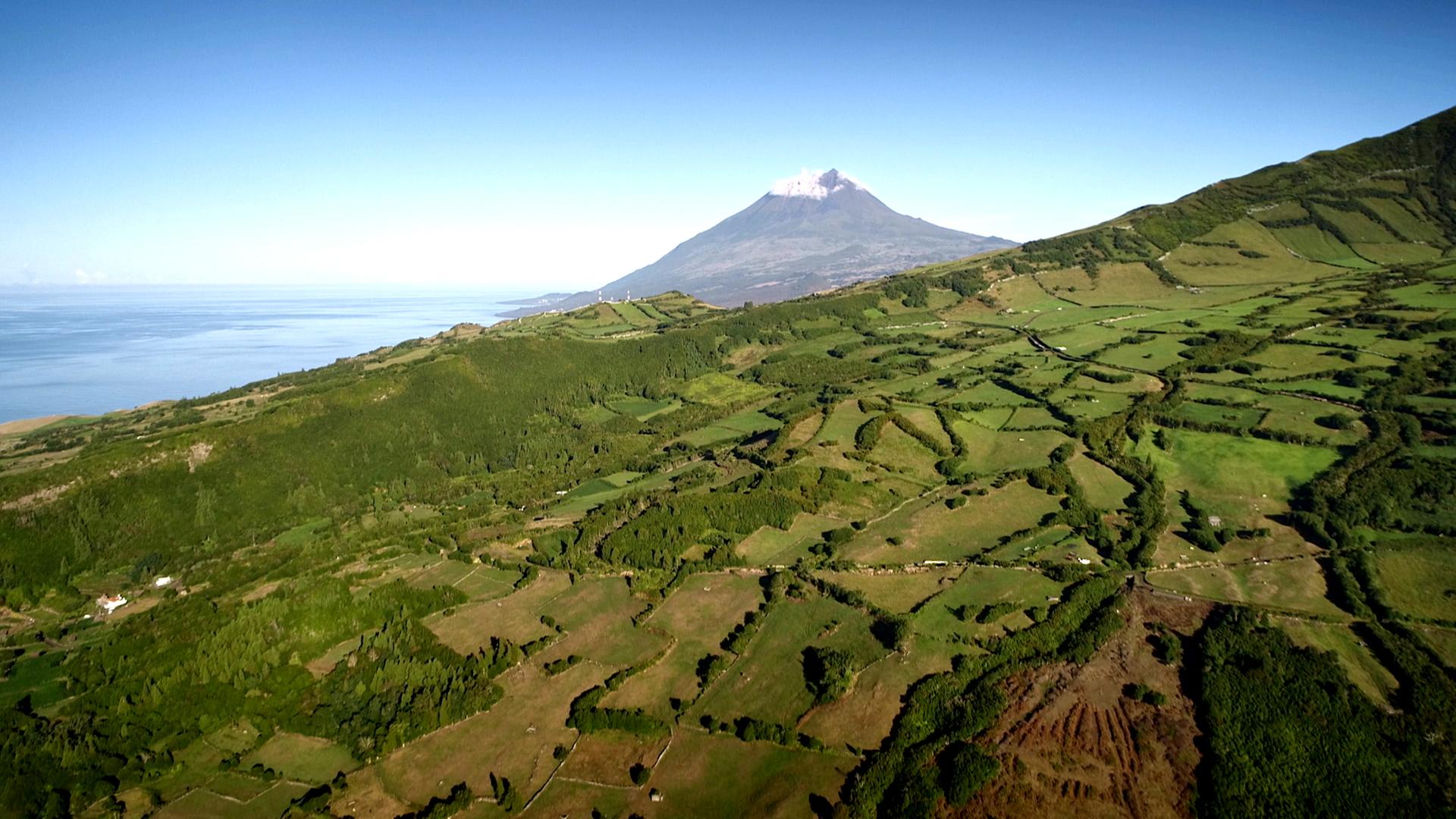 "Die Azoren - Inselparadies im Atlantik": Im Vordergrund sieht man einen bewaldeten Bergrücken. Dahinter ragt der Vulkan Ponta do Pico ins Bild.