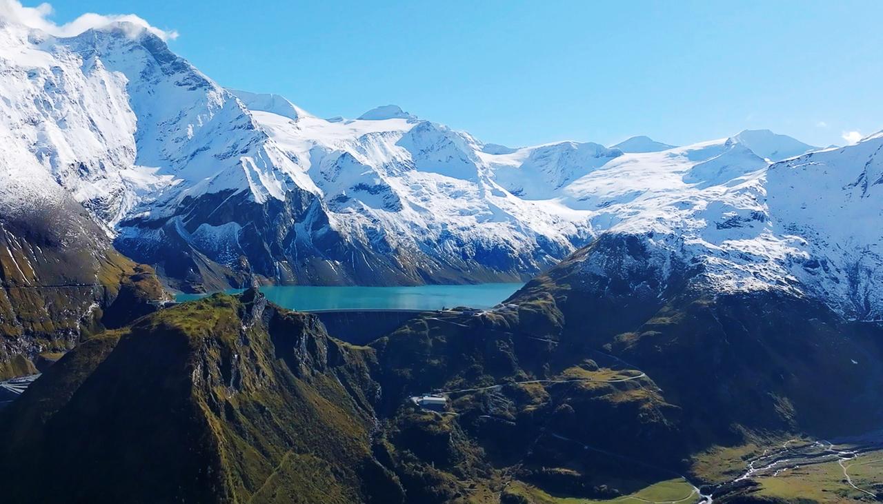 Unter blauem Himmel umschliesst eine Bergkette einen See.