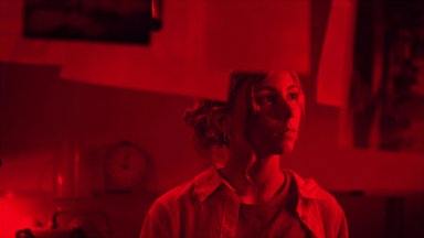 Sarah (Romy Amberg) entwickelt Bilder in der schwach rot beleuchteten Dunkelkammer.