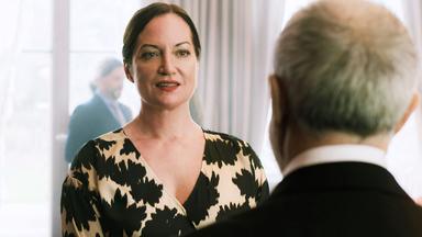 Eine Frau und ein Mann unterhalten sich. Der Mann steht mit dem Rücken zur Kamera.