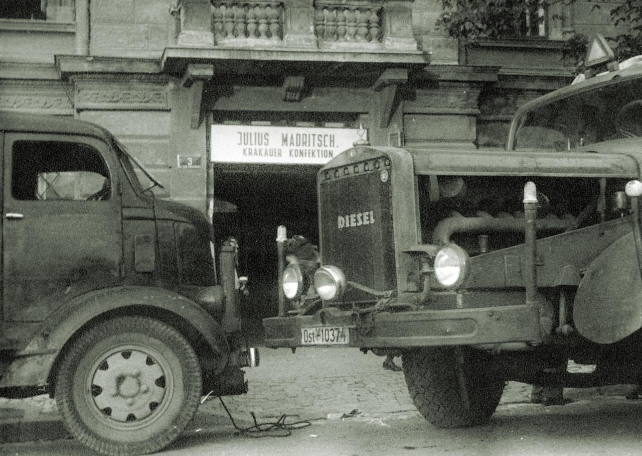 Historisches Foto: Zwei Transportfahrzeuge vor einer Werkstatt