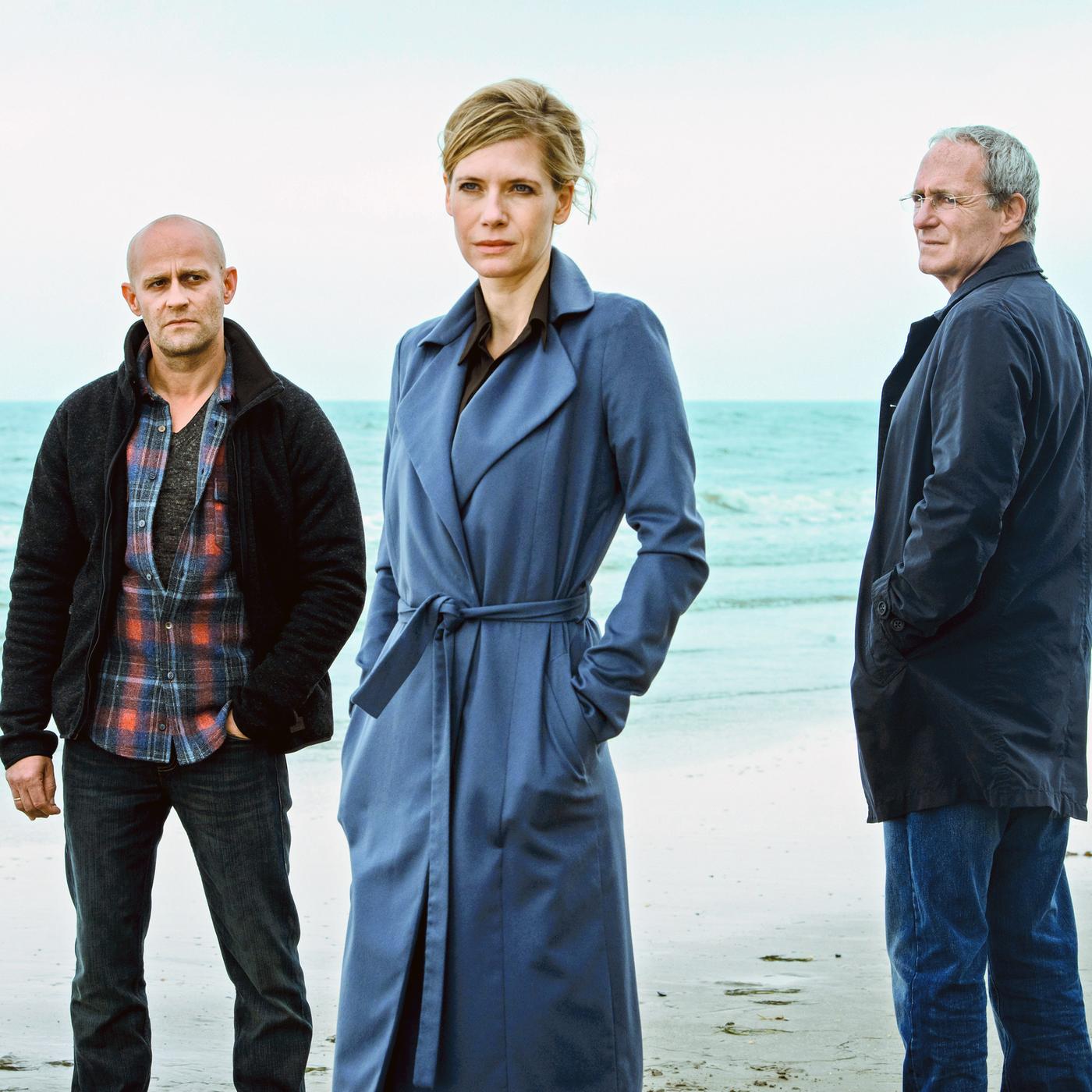 Zwei Männer und eine Frau stehen am Strand