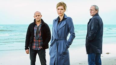 Zwei Männer und eine Frau stehen am Strand