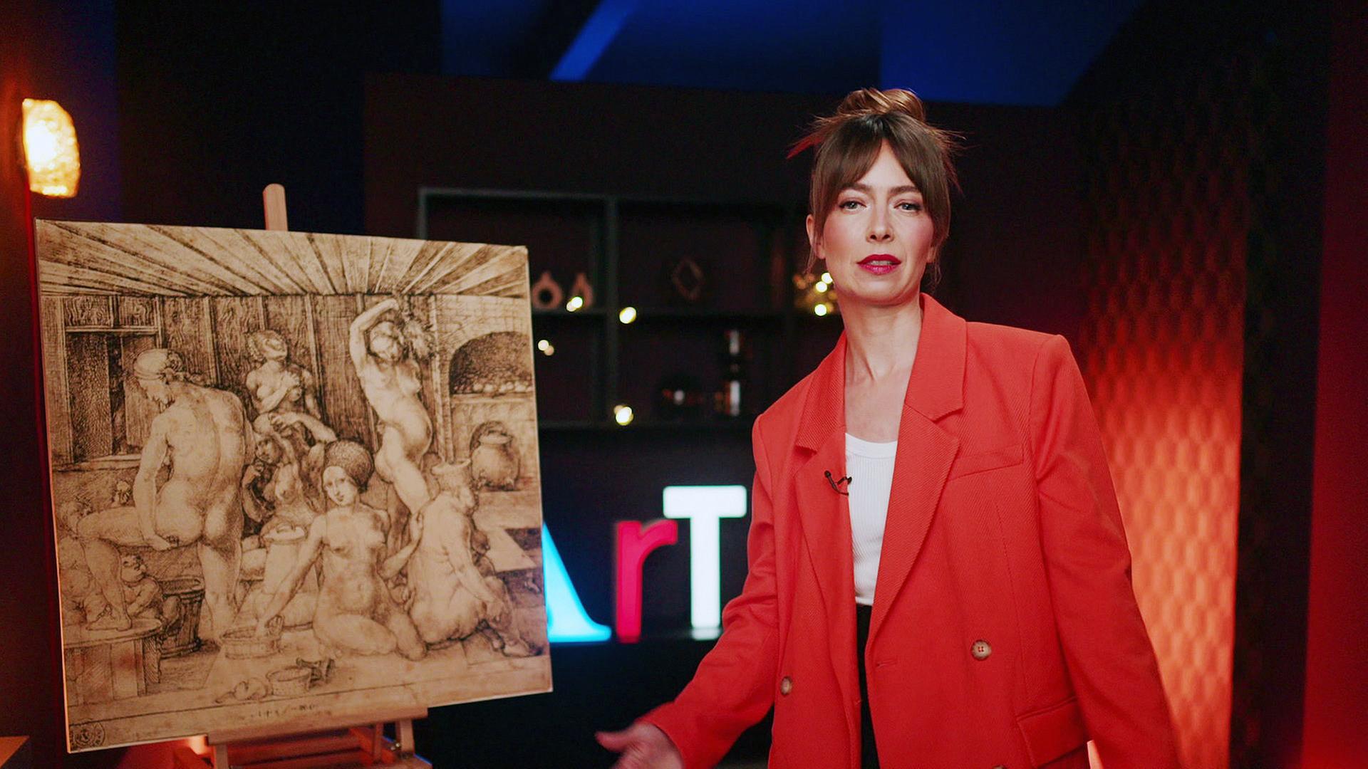 Eine Frau in einem roten Blazer steht neben einem Dürer-Stich mit nackten Menschen