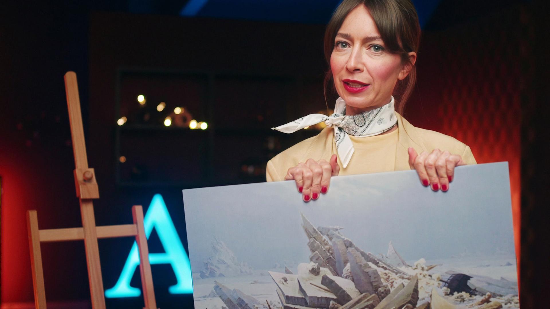 Bianca Hauda hält ein Gemälde von Caspar David Friedrich in der Hand.