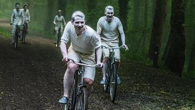 Lachend fahren Ike (Jakub Sprenger) und Sam (Marek Wroblewski) mit weiteren Jugendlichen auf Fahrrädern durch einen Wald. Sie sind über und über mit weißem Pulver bestreut.