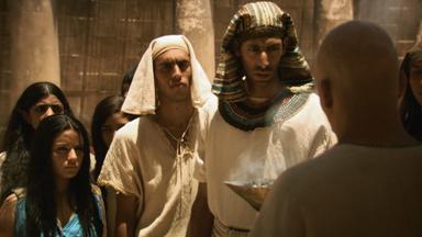 "Die glorreichen 10 - Die kolossalsten Konfrontationen der Geschichte": Spielszene: Echnaton redet auf einen Amun-Priester ein. Hinter ihm stehen zahlreiche Menschen.