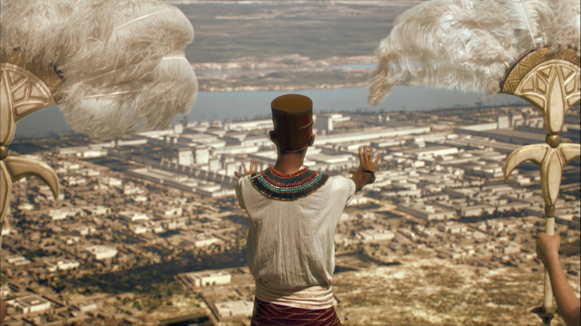 harao Echnaton steht mit dem Rücken zur Kamera auf einer Anhöhe und schaut auf eine Stadt. 