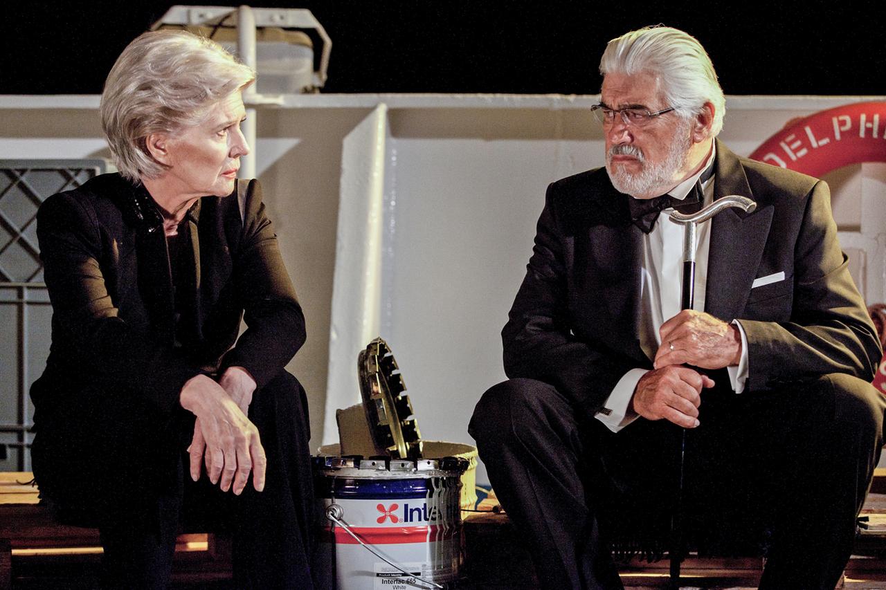 Paar sitzen in Abendrobe auf einem Schiffsdeck.